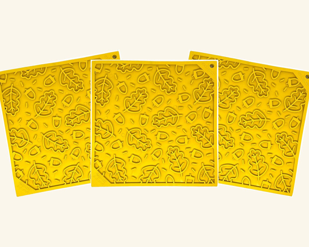 Three yellow SodaPup Autumn eMat lick mats with a fall leaves and acorns design