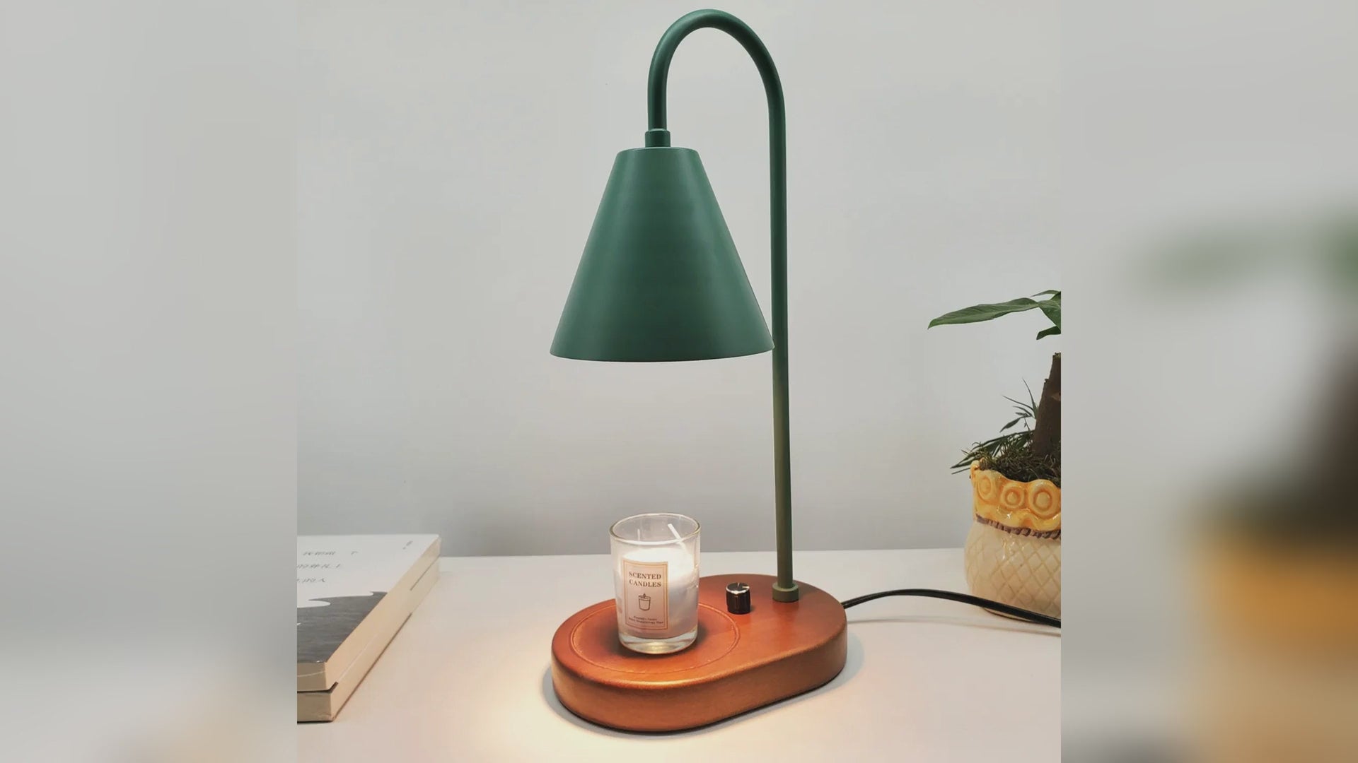 Electric candle warmer lamp lit over a jar candle, shown in green, black and white