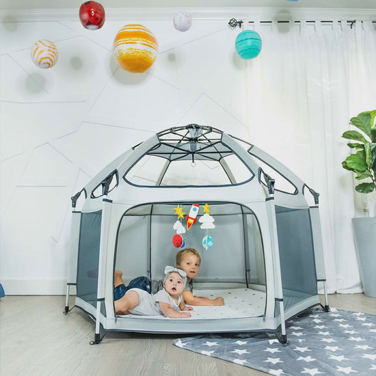Kids playing inside a mint Pop N Go playpen at a park